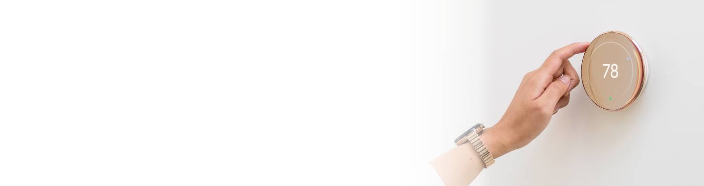 A person changing the temperature on their thermostat