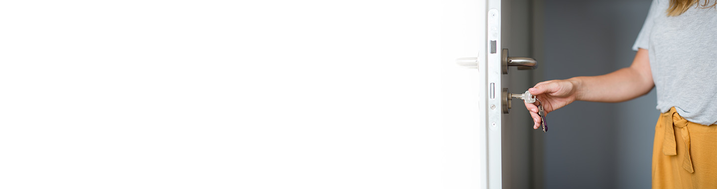 A woman holds a key in her hand, preparing to unlock a door.