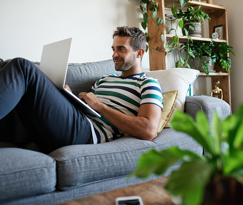 Man laying on the couch with his laptop