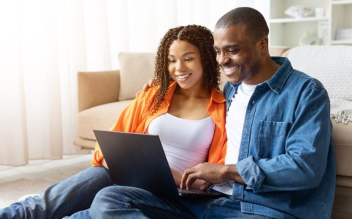 Homeowners using a laptop together to explore energy efficiency programs and home upgrade options.