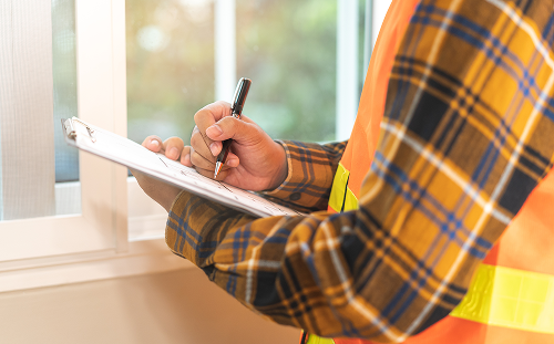 Technician recording notes during a home energy inspection for appliance recycling and efficiency improvements